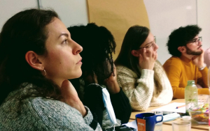 Foto der Teilnehmenden der Politik Akademie der Vielfalt Staffel 1 beim Workshop in Mainz. Die Teilnehmenden sitzen an einem Tisch und hören einem Vortrag zu.